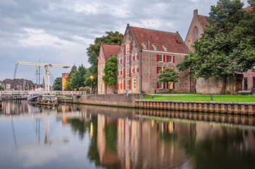 Fototapeta na wymiar Zwolle, The Netherlands, August 4, 2021: historic buildings, trees and a drawbridge reflect in the smooth water of Thorbecke canal on a summer evening