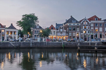 Fototapeta na wymiar Zwolle, The Netherlands, August 5, 2021: view across Thorbecke canal at twilight with street lanterns and historic houses