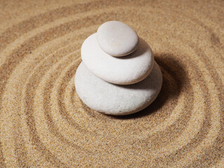 Fototapeta na wymiar Zen garden. Pyramids of white and gray zen stones on the white sand with abstract wave drawings.