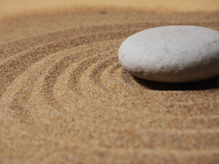 Zen garden. Pyramids of white and gray zen stones on the white sand with abstract wave drawings.