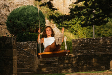 Gorgeous blonde woman enjoying on the swing during golden hour