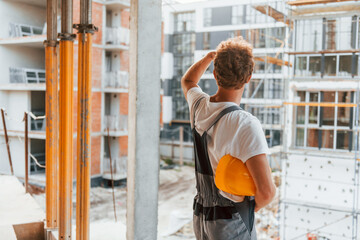 Big project. Young man working in uniform at construction at daytime