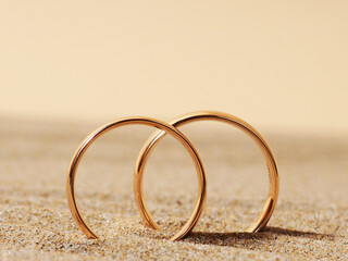 Two gold wedding rings in the sand, a honeymoon