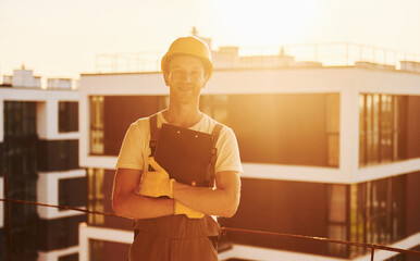 Building of modern city. Young man working in uniform at construction at daytime
