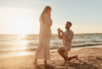 Fotobehang liefde en mensenconcept - glimlachende jonge man met verlovingsring die een voorstel doet aan een gelukkige vrouw op het strand © Syda Productions