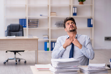 Young male employee unhappy with excessive work in the office