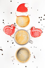 Three cups of coffee in shape of snowman with ginger cookie Santa hat and mittens. Christmas minimal creative layout. Top view