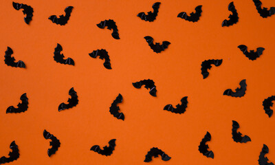 Naklejka na ściany i meble Black bats on an orange background. Halloween pattern. Background for design .