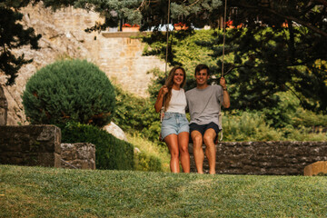 Beautiful couple enjoying the sunset on a swing hanging from a tree