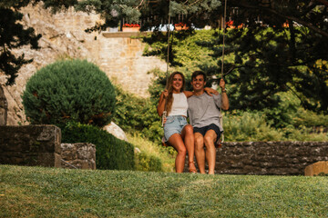 Beautiful couple enjoying the sunset on a swing hanging from a tree
