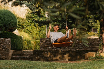 Young boy enjoying on the swing during golden hour
