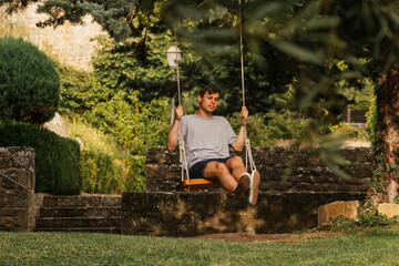 Young boy enjoying on the swing during golden hour
