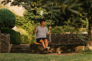 Young boy enjoying on the swing during golden hour