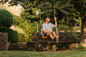 Young boy enjoying on the swing during golden hour