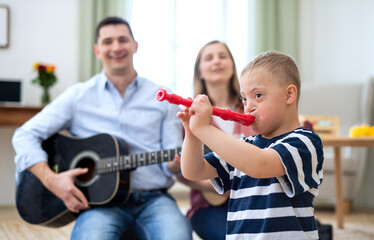 Cheerful down syndrome boy with parents playing musical instruments, laughing.