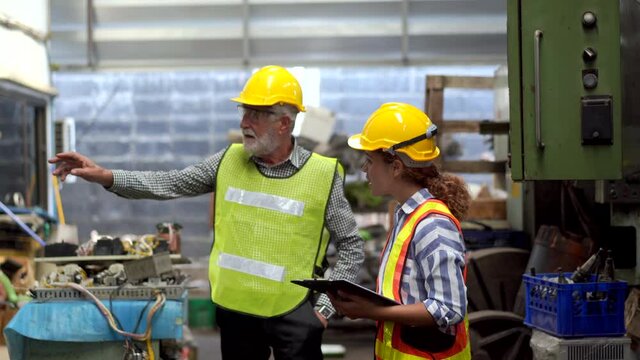 Male and female Industry engineer team in safety helmet working together in recycle electronic part factory. Woman foreman introduce factory department to senior manager. Machinery industrial concept