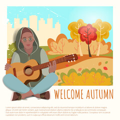 African american man sits with a guitar in a hood against the background of an autumn forest
