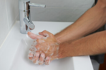 Hand washing with soap in a bathroom with white background