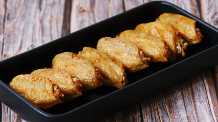Buffalo chicken wings in black plate on wooden background.
