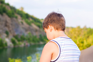 A child sits on the top of a beautiful canyon and looks at the water in it. The bank of the canyon.