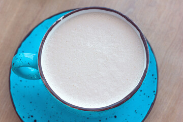 Latte raff coffee with beautiful froth in a blue cup close-up, morning drink sweet breakfast, copy space for text