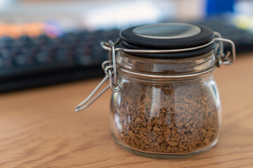 Instant coffee in a glass jar on a desktop on a keyboard background