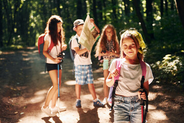 Posing for the camera. Kids strolling in the forest with travel equipment