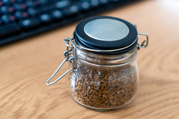 Instant coffee in a glass jar on a desktop on a keyboard background