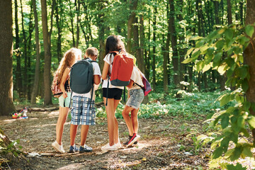 Naklejka na ściany i meble Kids strolling in the forest with travel equipment