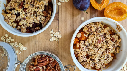 Thanksgiving baked crumble with apricot and plum fruit, spices, pecan nut and rolled oat on wooden table. Top view, close up. DIY
