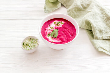 Red vegetarian beet soup in white bowl with sour cream