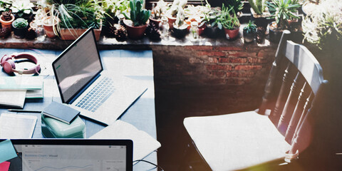 Naklejka na ściany i meble Workspace table with computer laptops and green houseplants