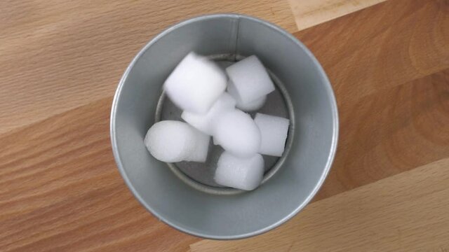 Plastic waste falls into a metal trash can on a wooden surface. Garbage collection for recycling concept. Close up. Slow motion