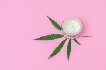 Top view of cosmetic skin care cream with hemp extract on pink background with copy space