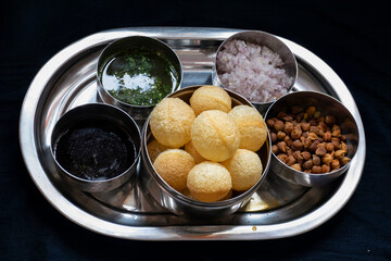Stock photo of traditional famous Indian street snacks or food panipuri.it is also known as puchka, golgappa, spicy water ball.Panipuri plate arranged with different sources ,onion and chickpeas.