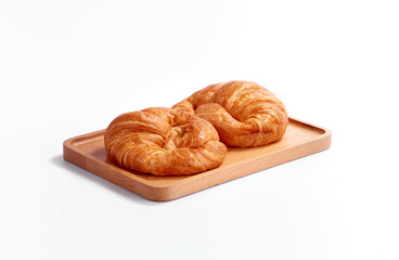 Croissant in wooden plate, on white background. Nobody. Soft lighting