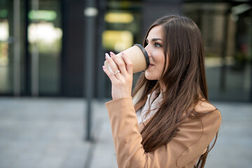 Young businesswoman drinking coffee while walking