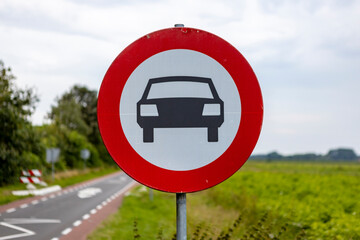 Dutch sign with red band showing an icon of a car meaning no entry for personal vehicles approaching a traffic bump too high to go over