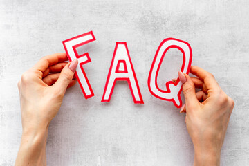 Hands with faq - frequently asked questions - paper letters, top view