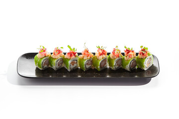Shrimp Sushi Roll on black slate plate. Luxury maki sushi roll with cream cheese and shrimp inside. Seafood sushi roll topped with spicy scallop. Isolated on white background.