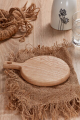 Fototapeta na wymiar Mockup for product, food and beverage. Wooden plate in burlap, glass of water on wooden table. Clean. Nobody