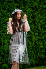 Young beautiful woman in hooded raincoat on rainy day