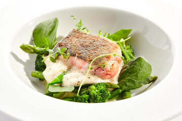 Panfried Fish with broccoli and green spinach. Healthy roasted cod with asparagus espuma. Fried Fish on white restaurant plate isolated on white background.