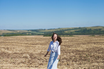 Happy brunette woman in nature, walking in the field outdoors, smiling