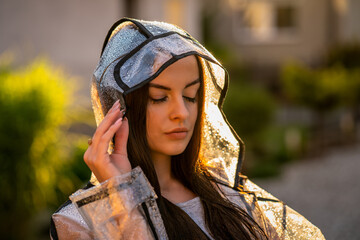 Young beautiful woman in hooded raincoat on rainy day