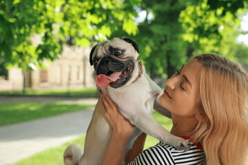 Woman with cute pug dog outdoors on sunny day. Animal adoption