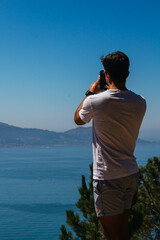 A boy taking photos and selfies during a hike in the mountains overlooking the sea