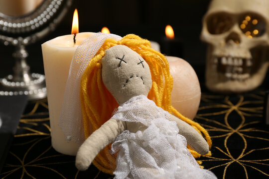 Voodoo doll pierced with pins and candles on black mat. Curse ceremony
