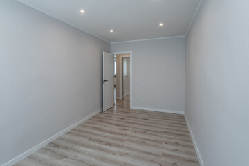Contemporary interior of room in luxury renovated apartment. White walls. Parquet floor. Opened door to hall.
