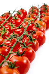 Close-up of bunches of ripe red cherry tomatoes on white background.